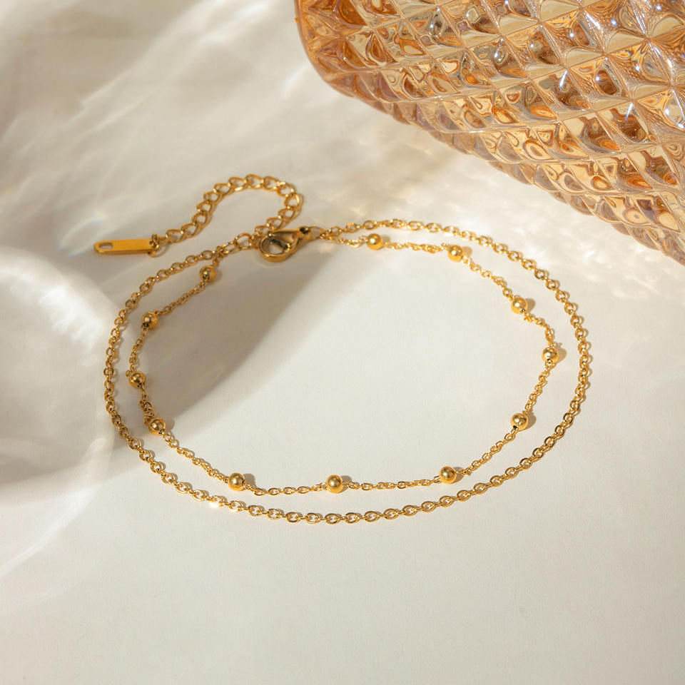 Gold Anklet white surface with a textured gold object in the background