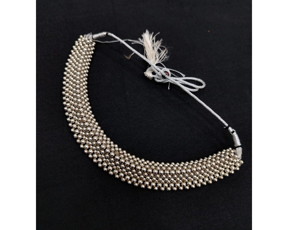 Silver beaded necklace on a black background