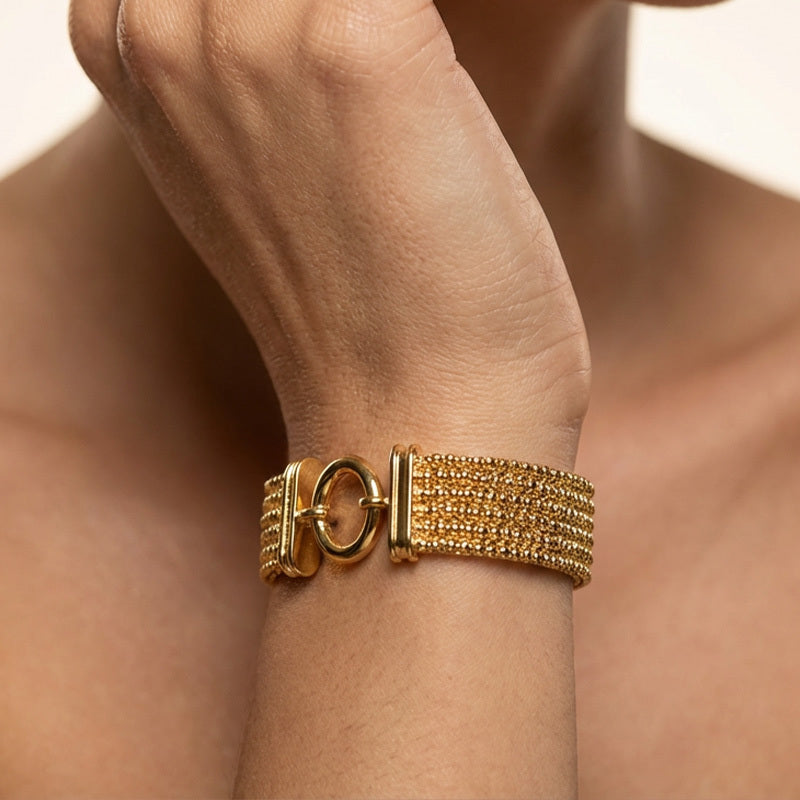 Gold bracelet on a wrist with a blurred background