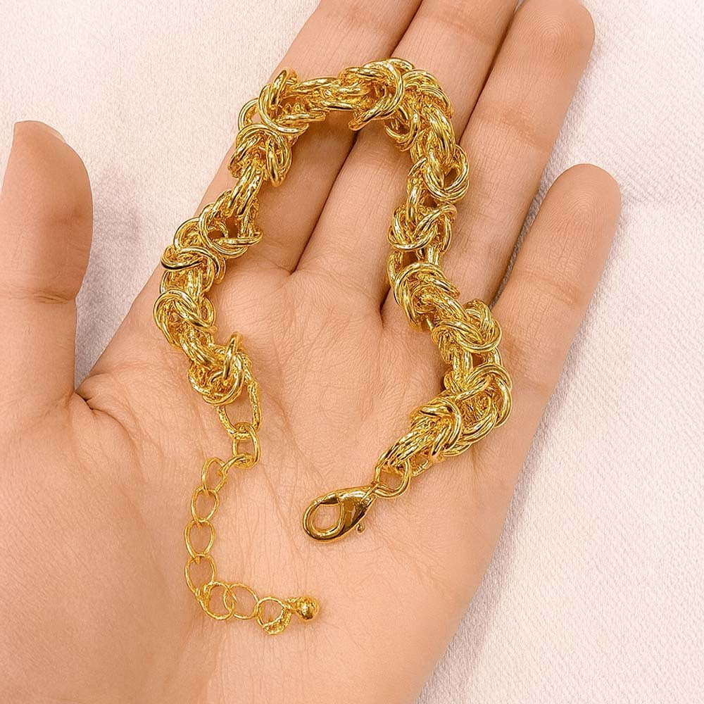 Gold chain bracelet on a hand against a light background