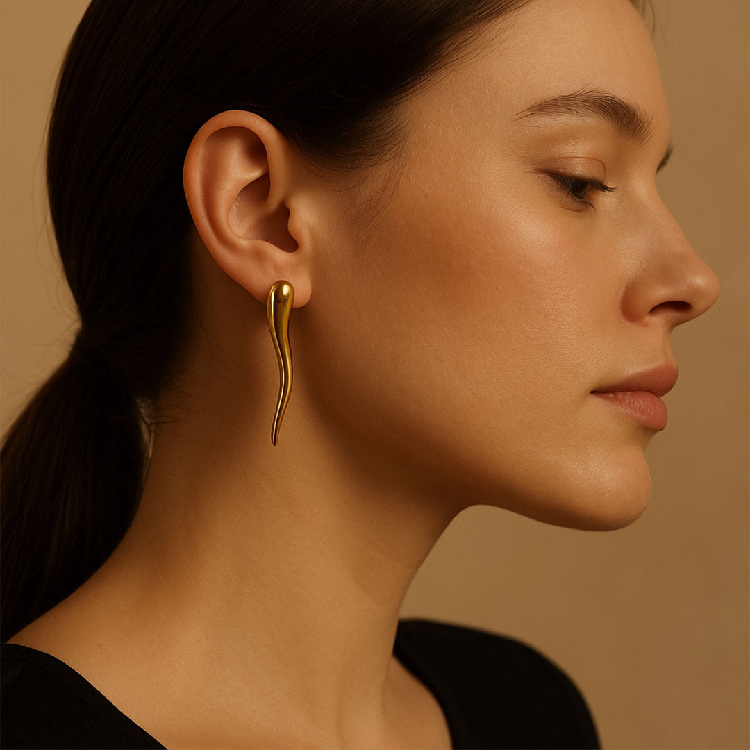 Woman wearing a gold earring against a beige background