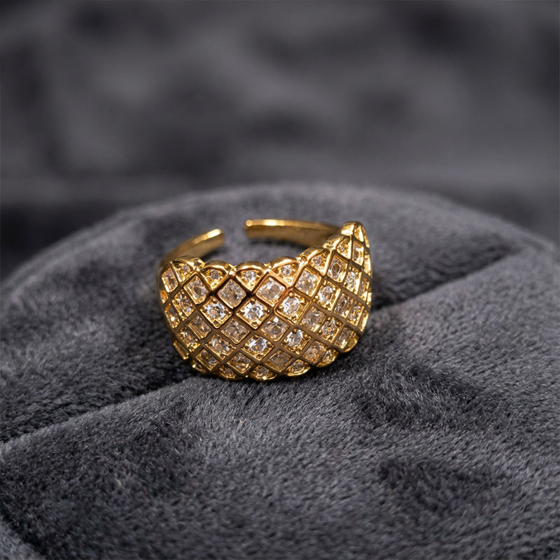 Gold ring with diamond lattice design on a gray textured surface
