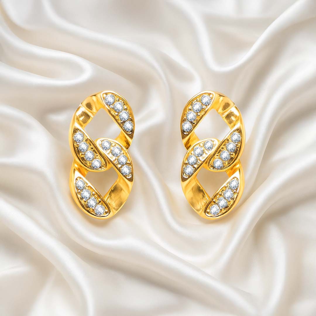 Gold earrings with diamond accents on a satin background