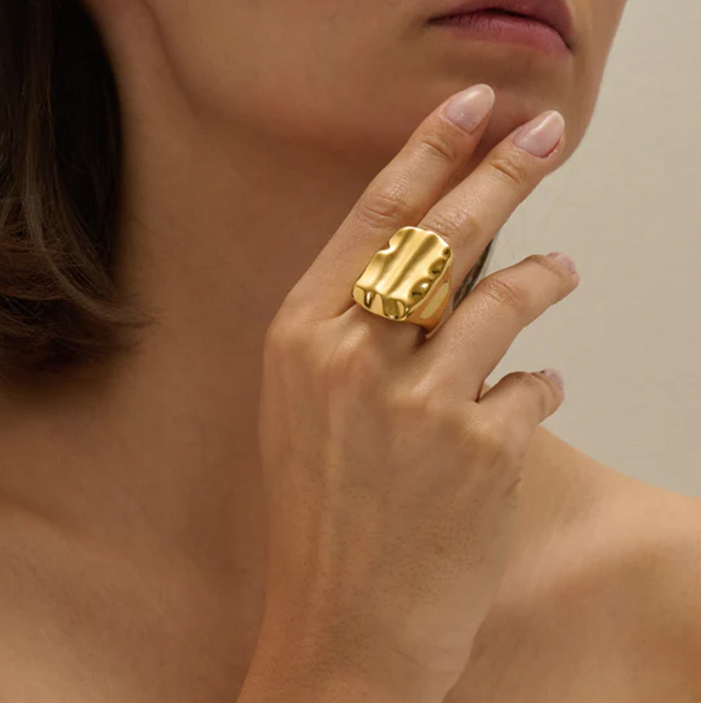 Gold ring on a hand with a neutral background