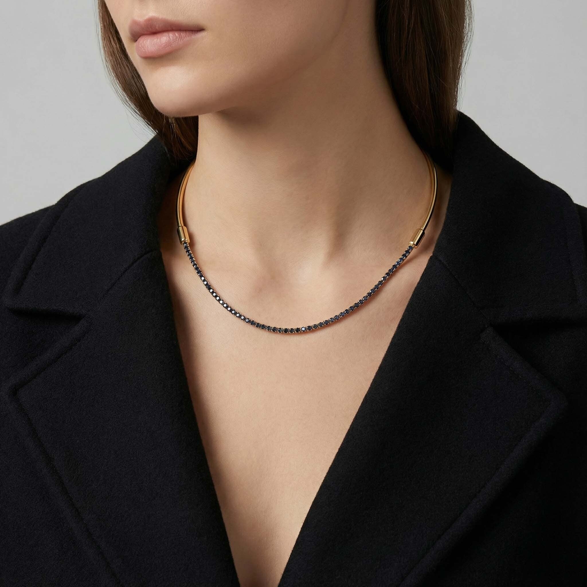 Woman wearing a sleek gold necklace with crystal detailing styled with a black outfit