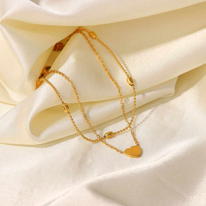 Gold bracelet and necklace set on a soft beige fabric background