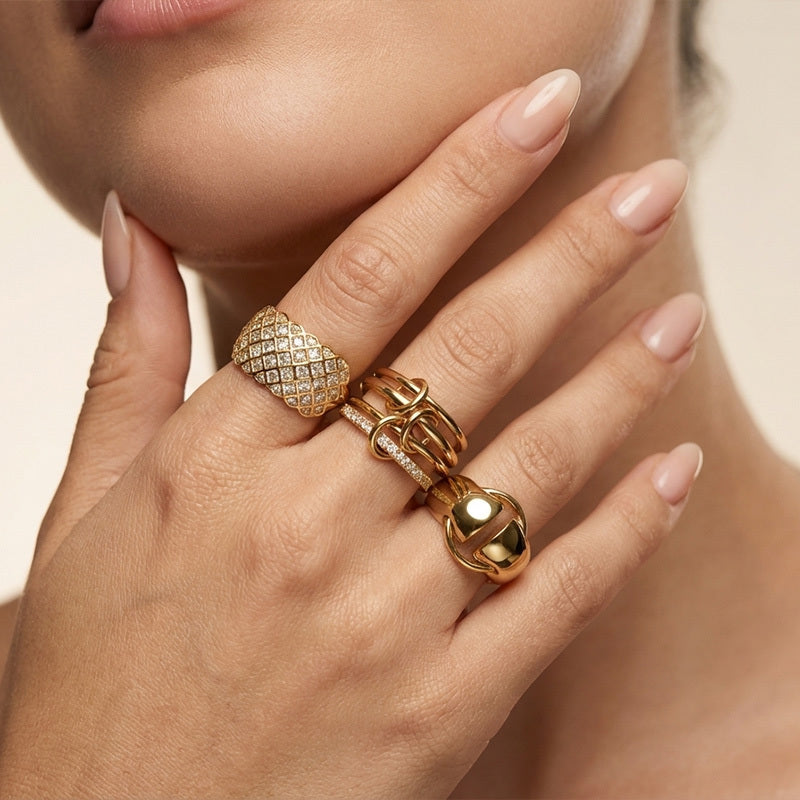 Close-up of a hand wearing gold rings with intricate designs.