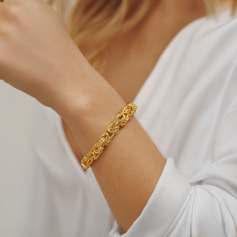 Gold bracelet on a person's wrist with a blurred background