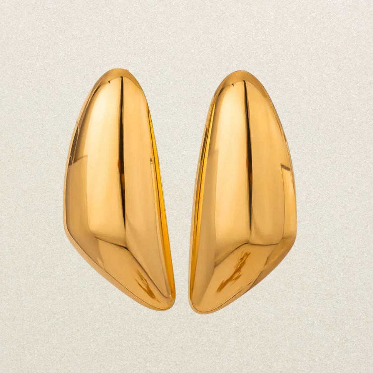 Pair of gold earrings for women on a light beige background