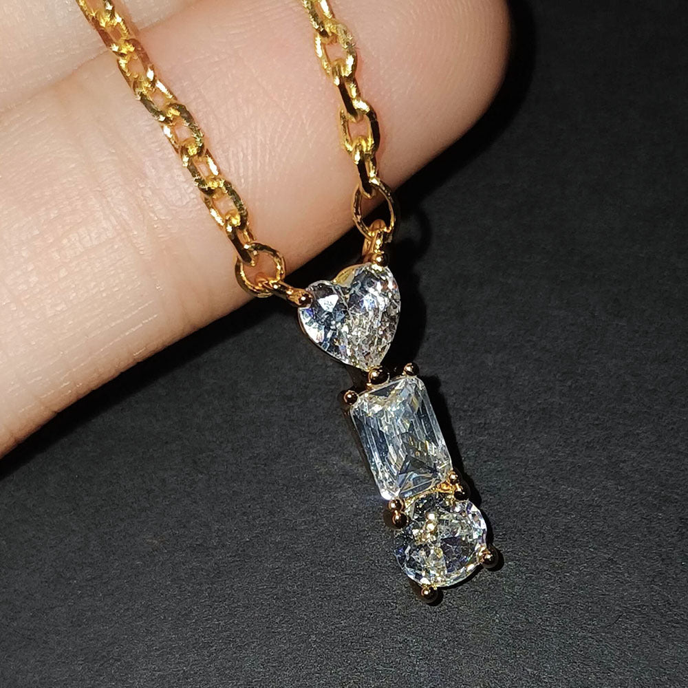 Gold necklace with heart and rectangular diamond pendants on a dark background