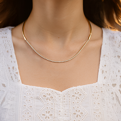 Gold necklace worn by a person with a white lace top