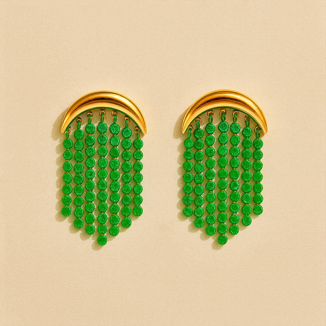 Pair of gold earrings with green gemstone drops on a beige background