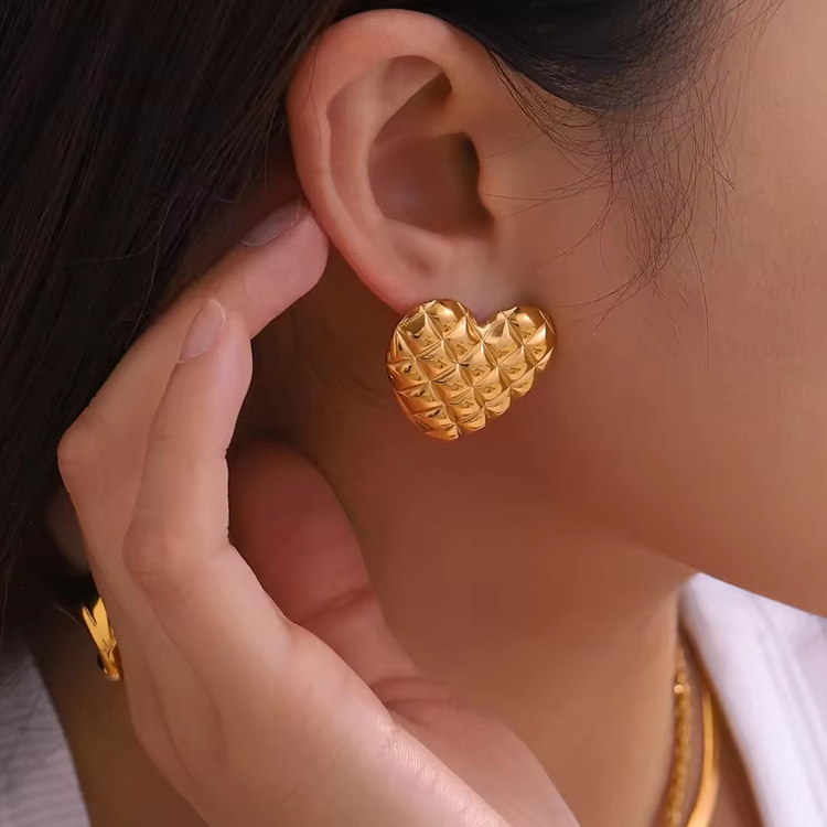 Gold heart-shaped earrings for women worn by a person