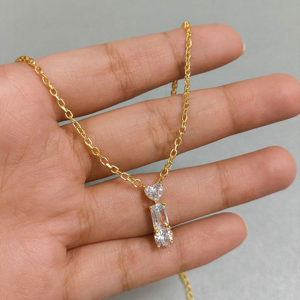 Gold necklace with a diamond pendant held by a hand against a neutral background