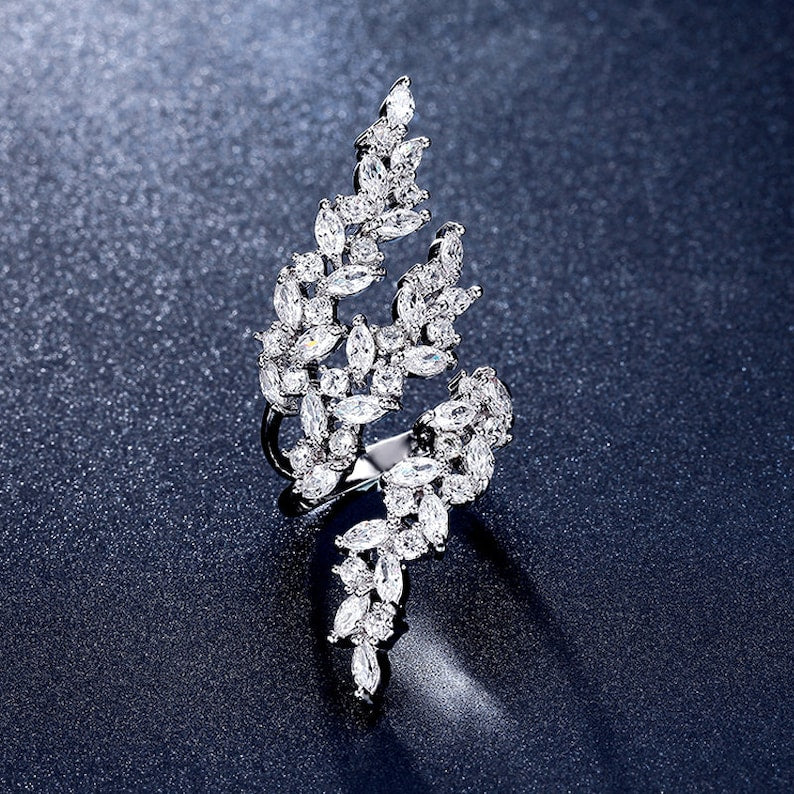 Diamanté leaf-shaped ring on a dark textured background
