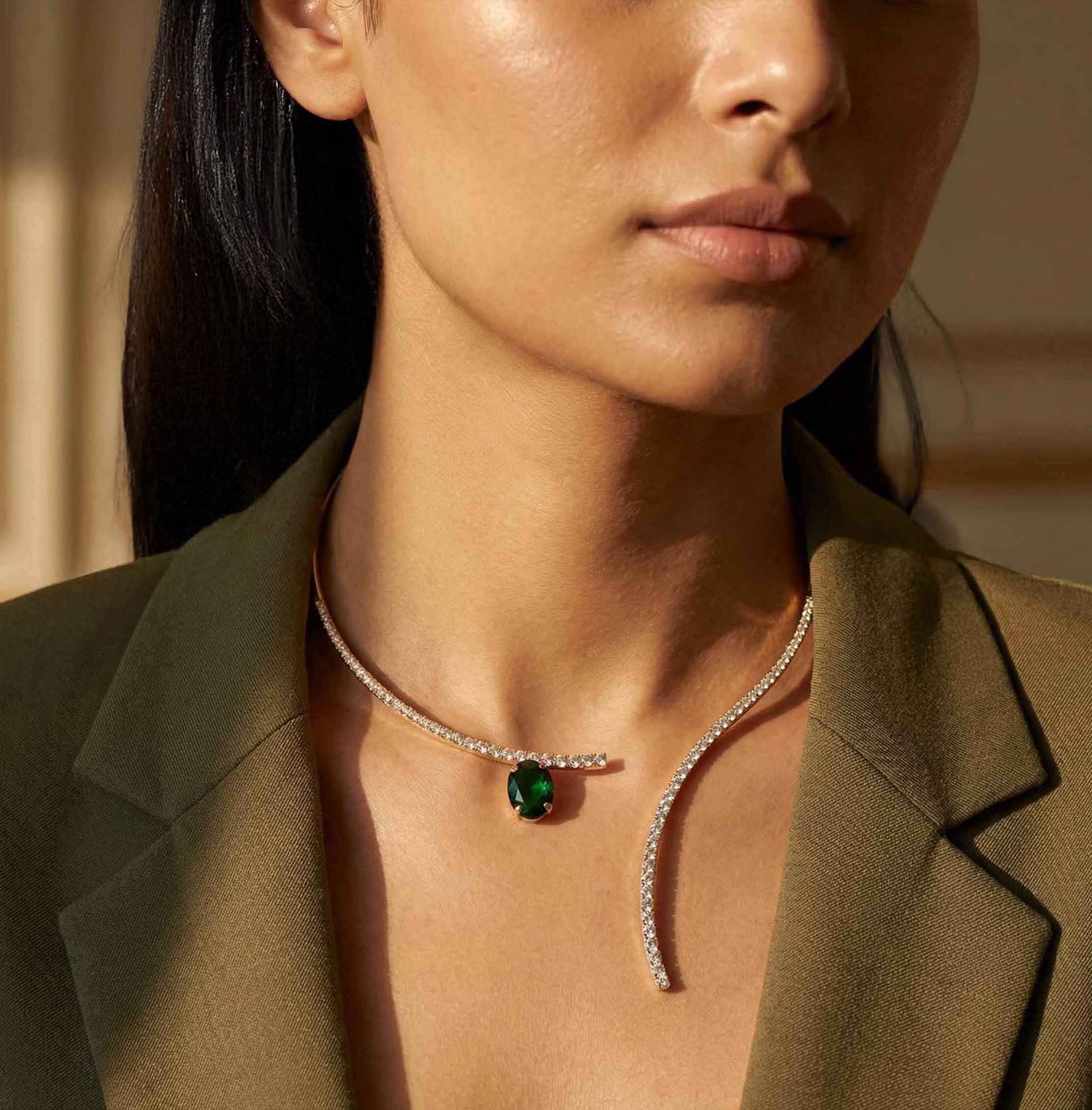Woman wearing a minimalist gold y necklace for women with a green gemstone in a close-up shot.