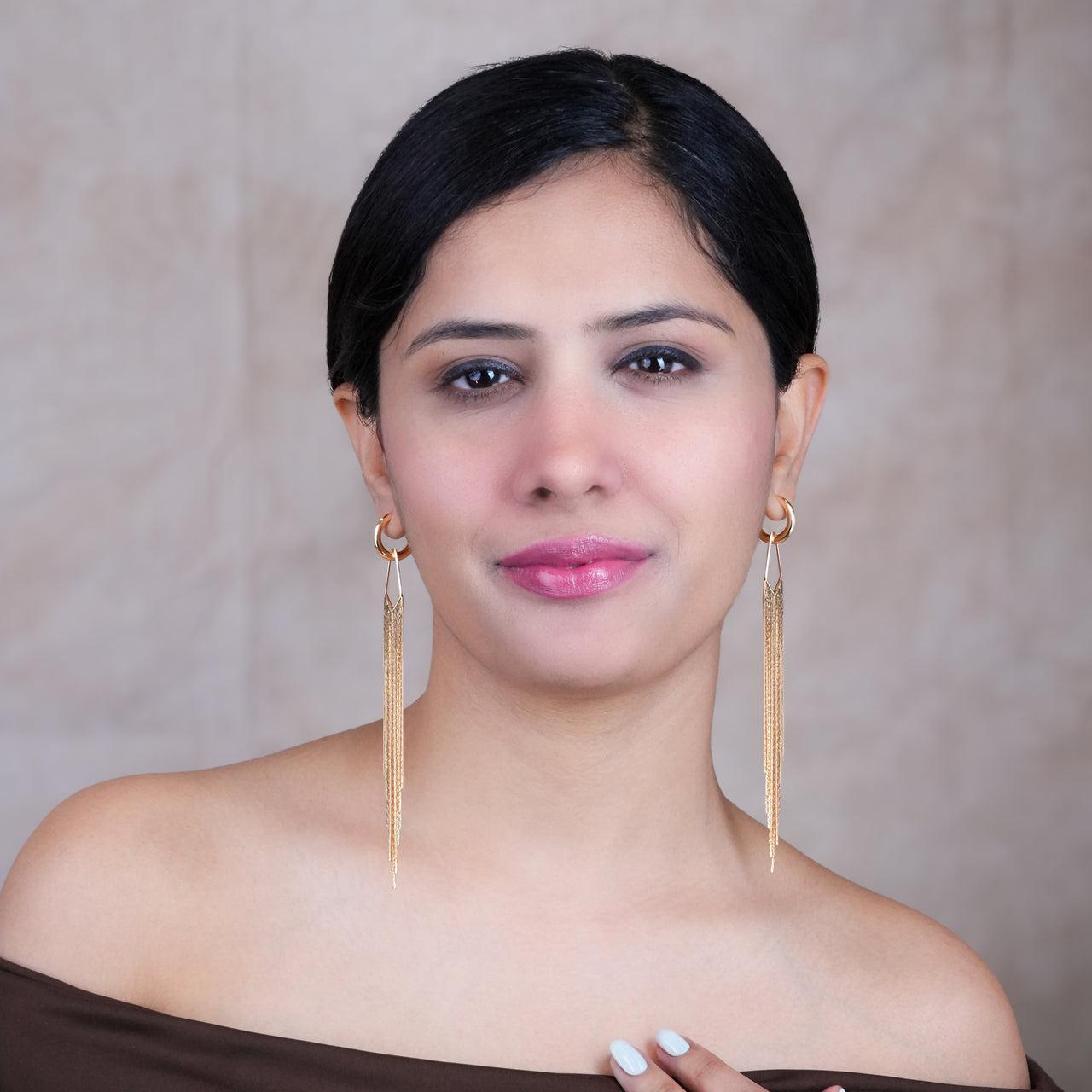 Woman wearing gold earrings against a neutral background