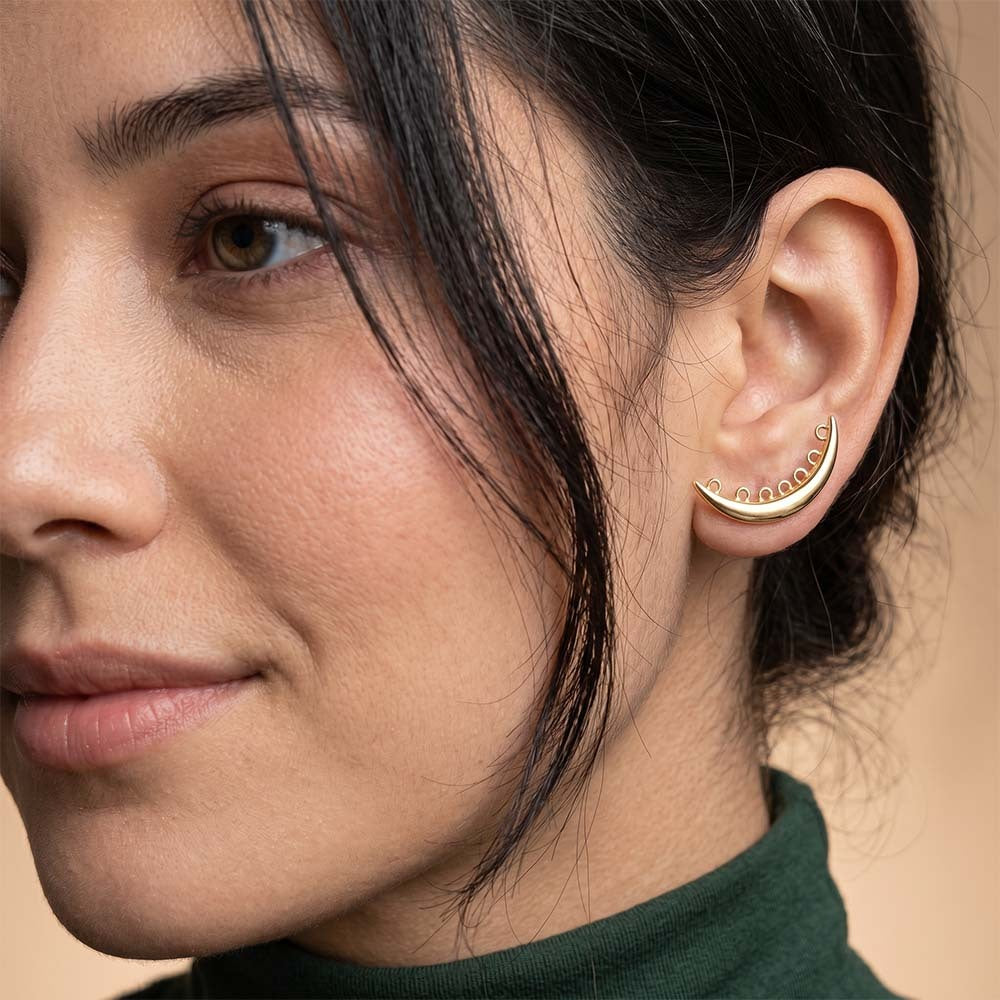 Close-up of a woman wearing a gold earring with a beige background