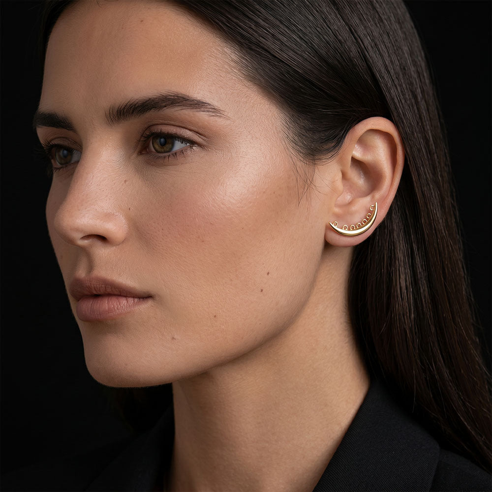 Close-up of a woman wearing gold hoop earrings against a black background
