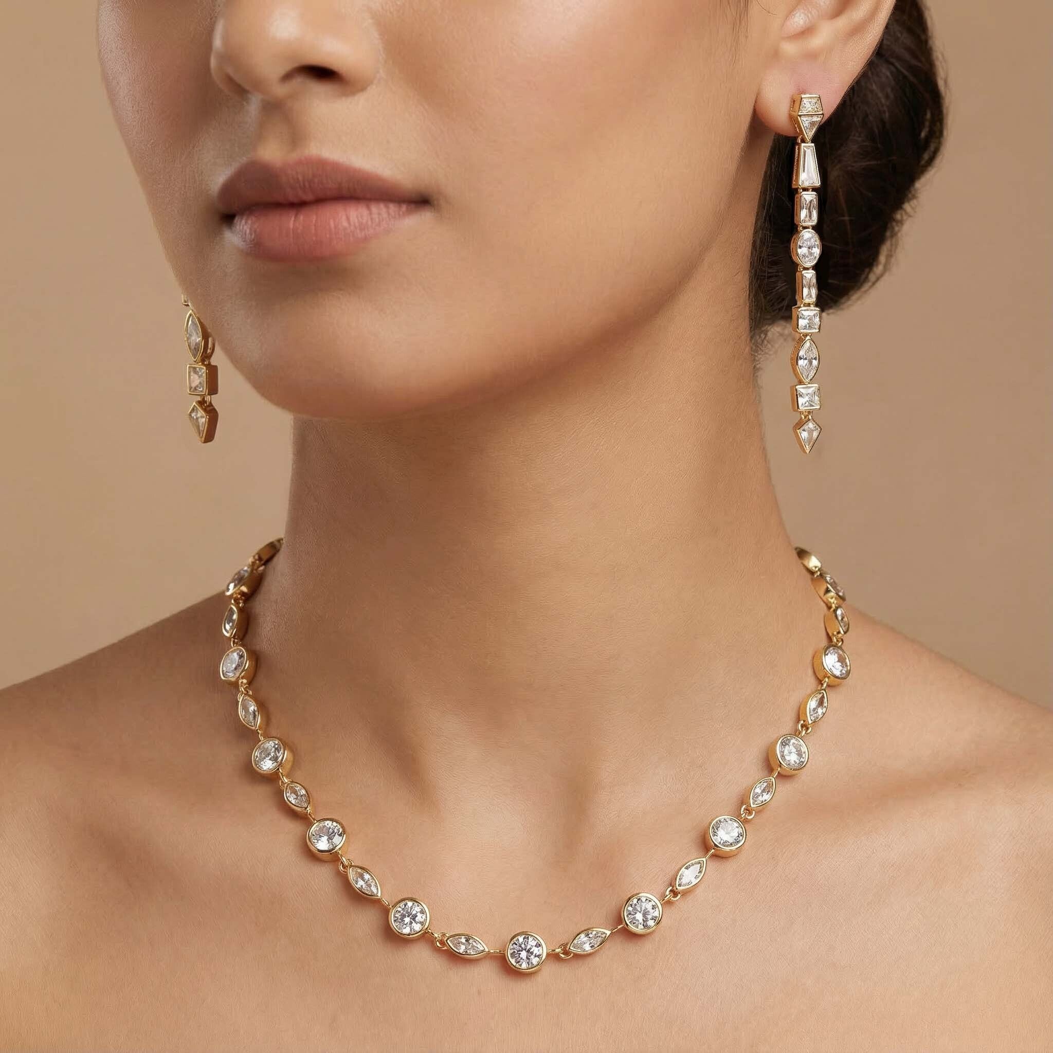 Close-up of a woman wearing a gold necklace and earrings against a beige background