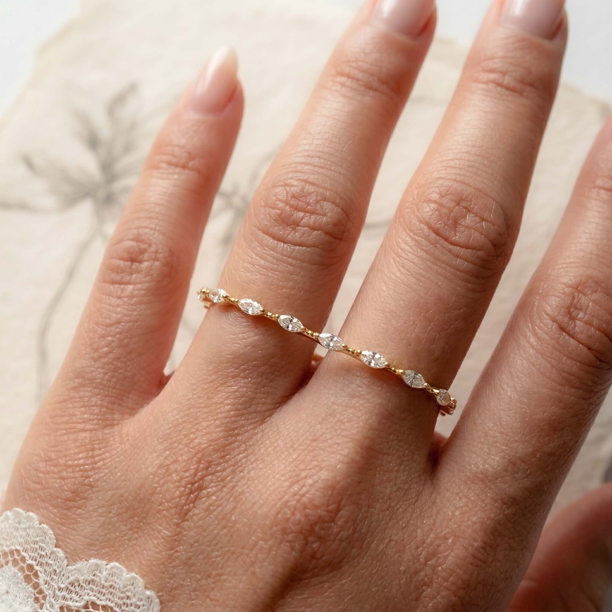 Gold ring with small diamonds on a hand against a neutral background