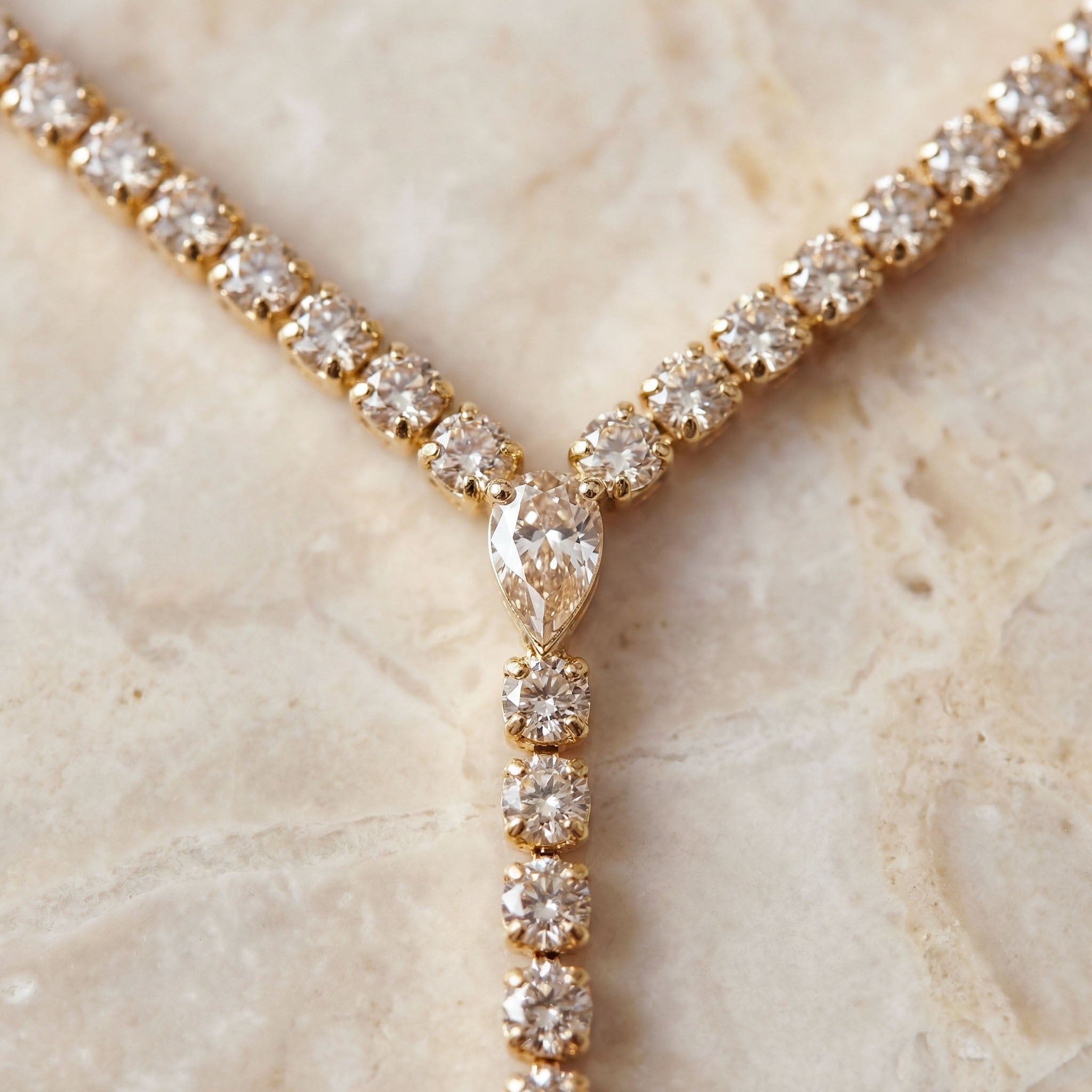Gold necklace with diamond pendants on a marble surface