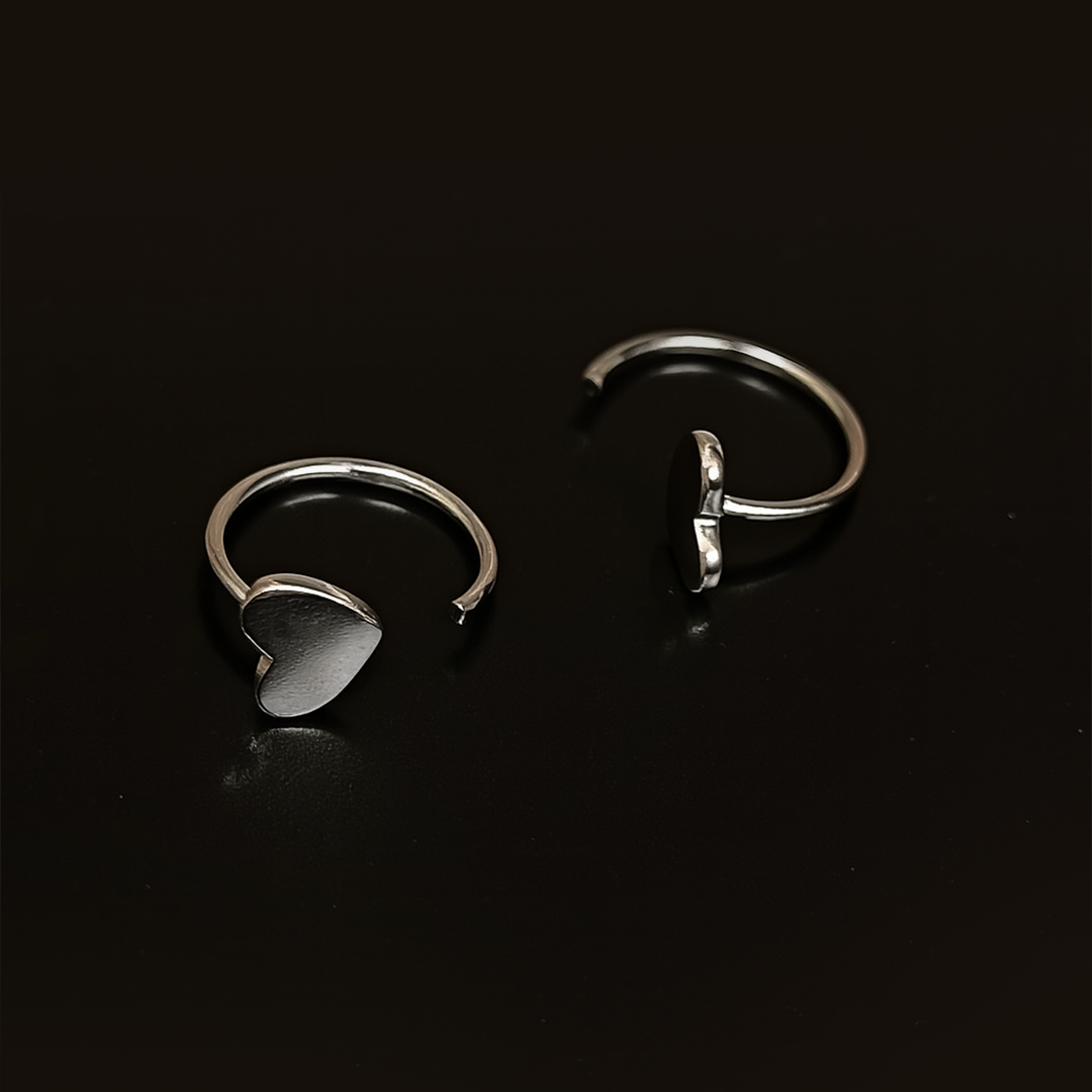 Two silver earrings for women on a black background