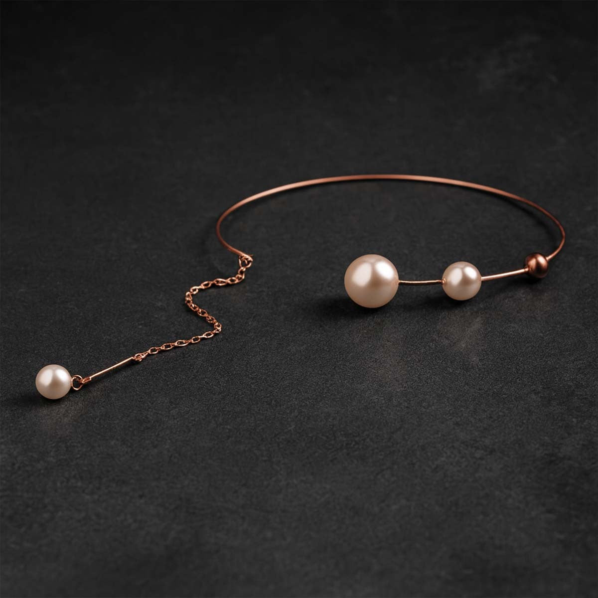 Rose gold necklace with pearls on a dark background