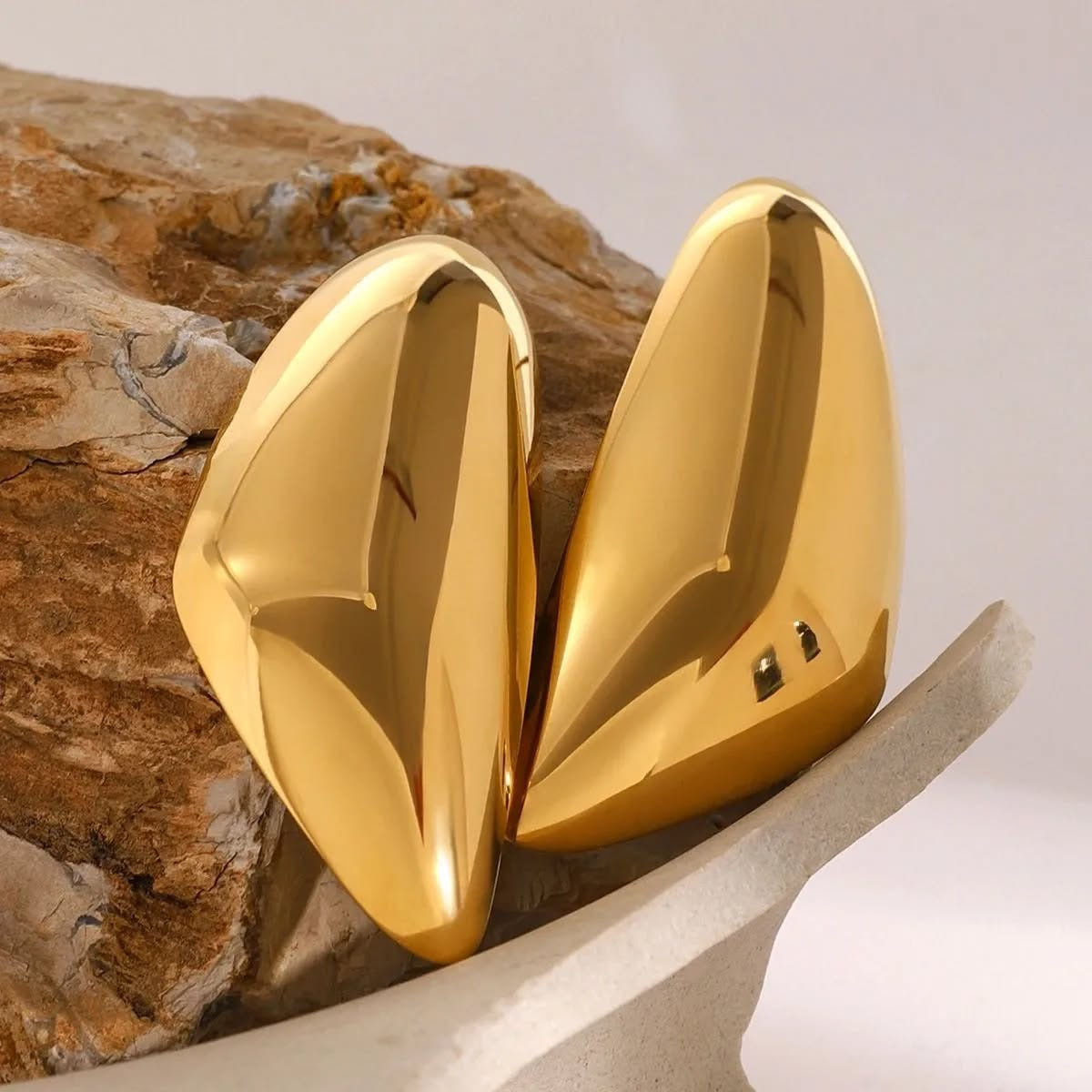 Gold earrings for women on a textured surface