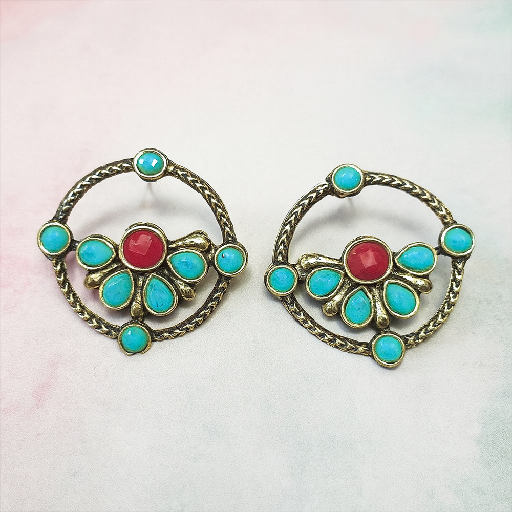 Pair of earrings with turquoise stones and a red center on a light background