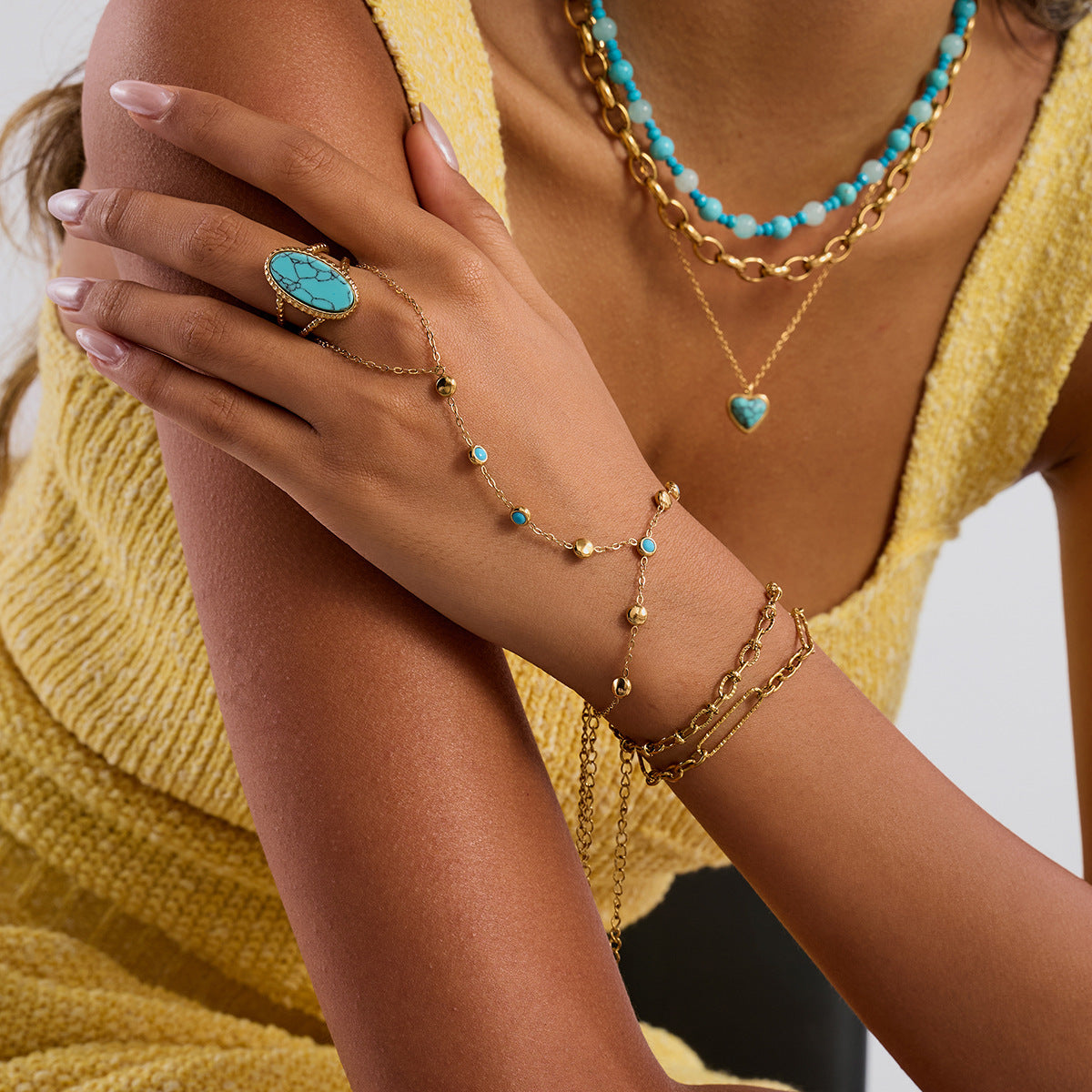 Close-up of a person wearing gold and turquoise jewelry on a blurred background