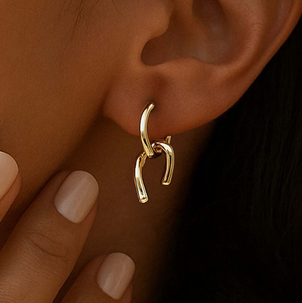 Gold earrings for women worn on an ear with a blurred background