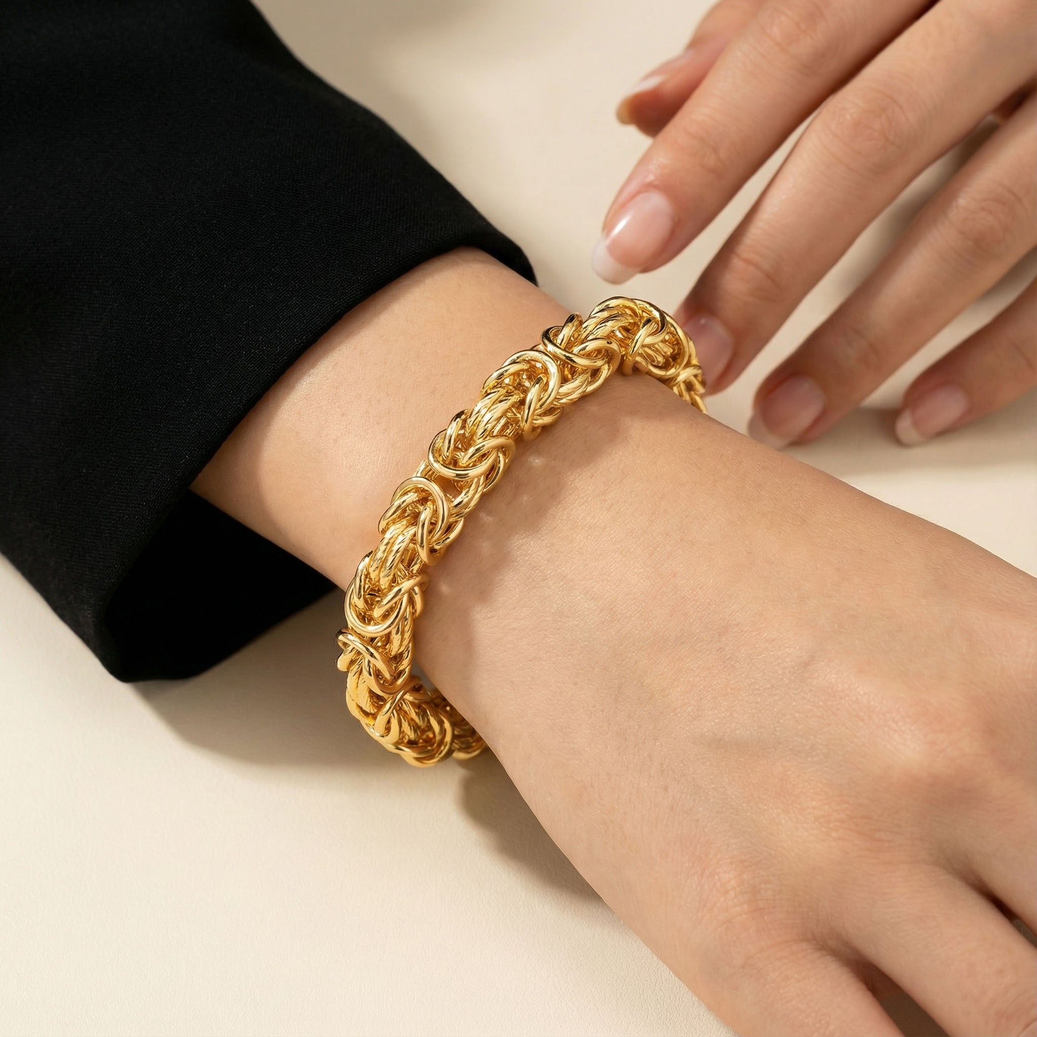 Gold bracelet on a wrist with a neutral background