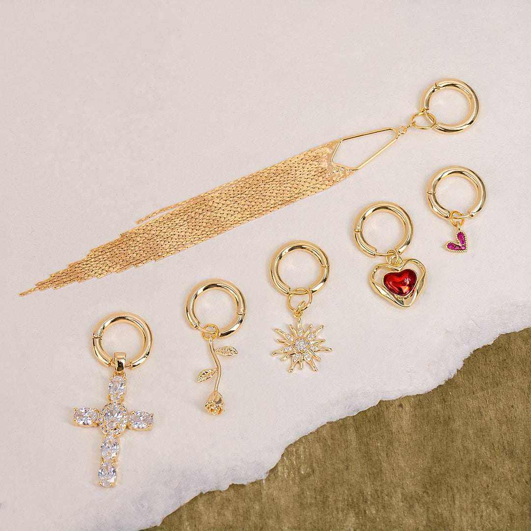 Set of gold earrings with various designs on a textured beige background