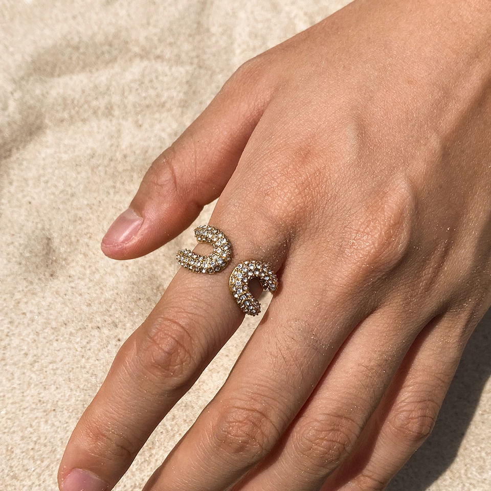 Hand wearing two diamond rings on a beige background