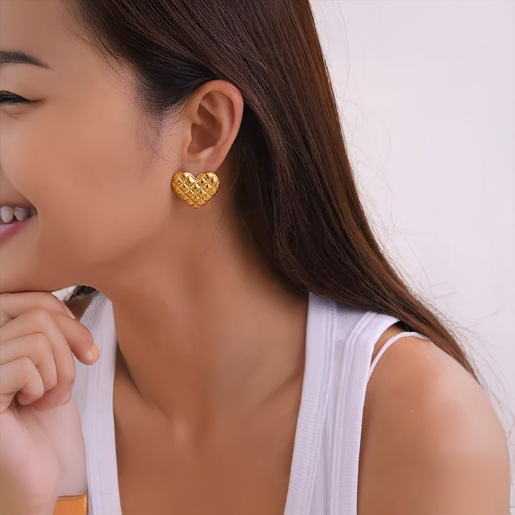 Woman wearing 18k gold  plated heart-shaped earrings for women with a blurred background