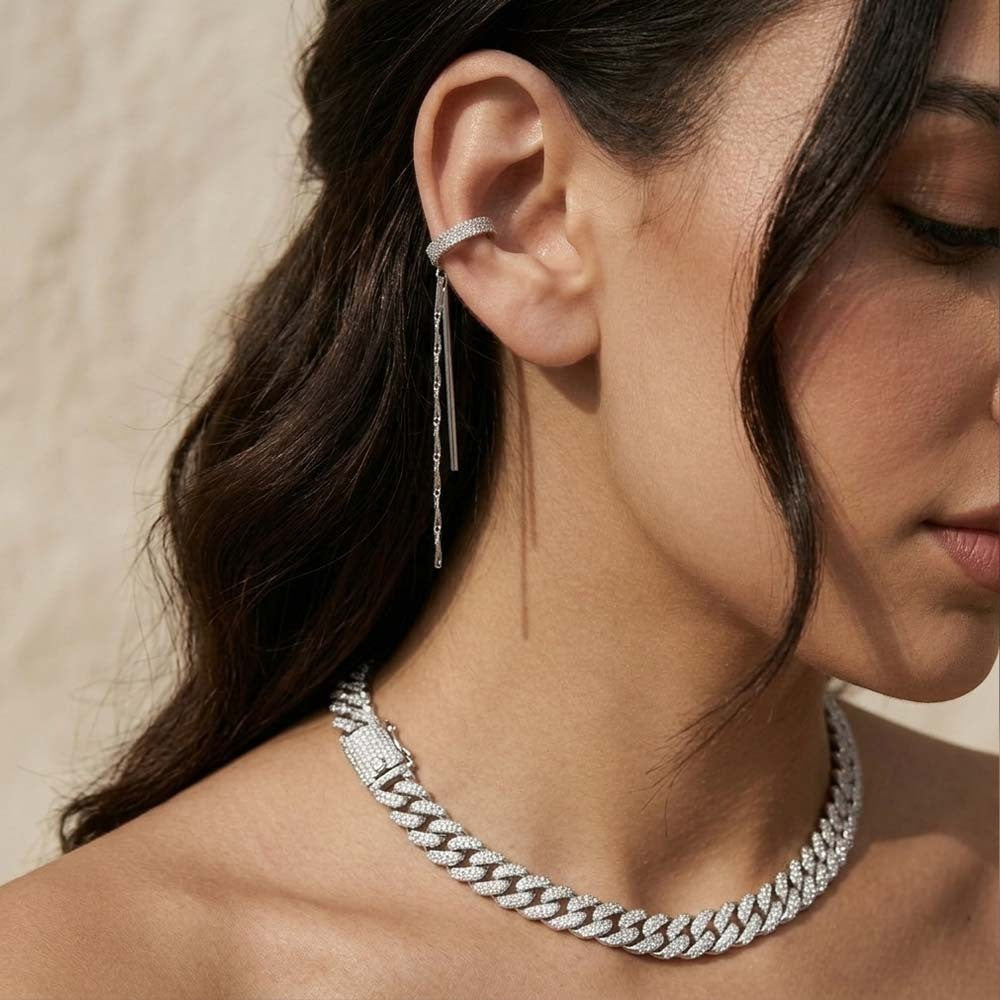 Close-up of a woman wearing a silver earring and necklace against a neutral background