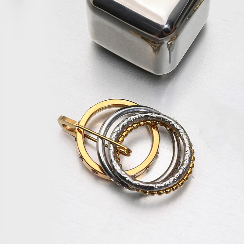 Jewelry with interlocking rings in gold and silver on a light gray background