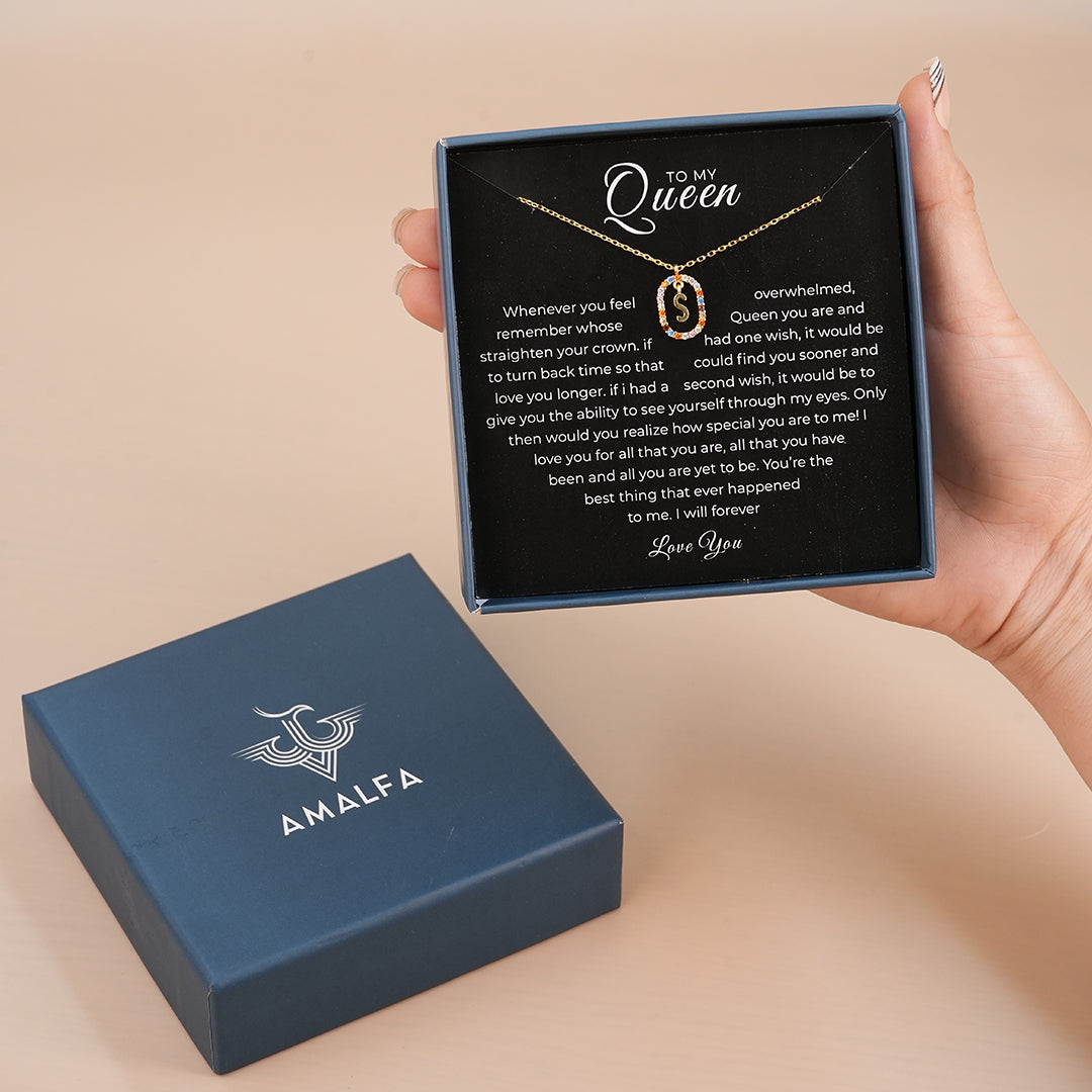 Initial necklace with sentimental message in a box held by a hand, next to an AMALFA branded box.
