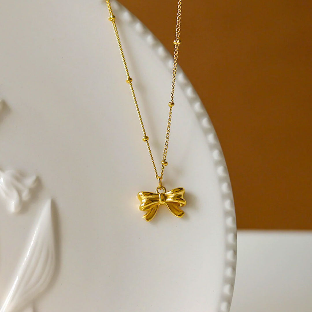 Gold chain necklace with a bow pendant