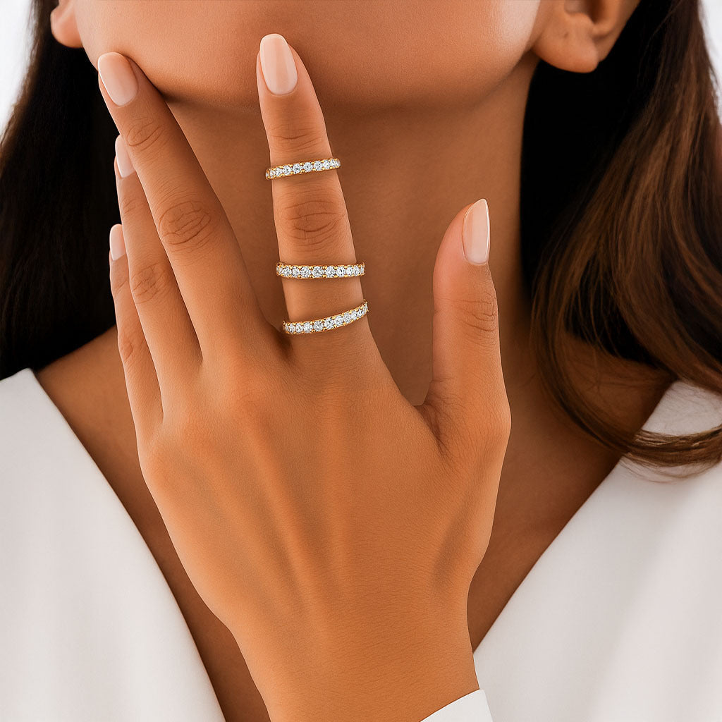 A woman's hand wearing a sparkling gold multi-band ring with crystal detailing, styled for Christmas outfits and festive holiday looks.