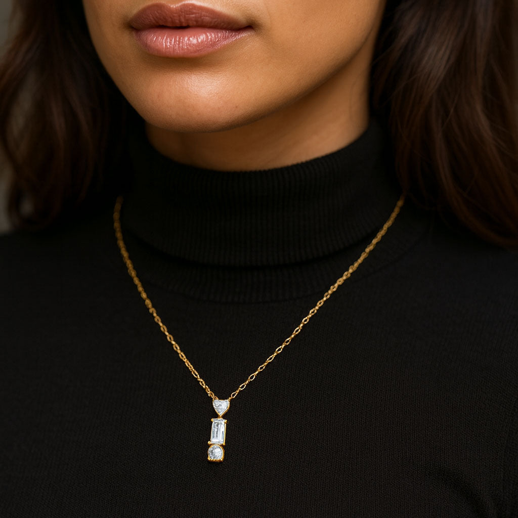 Gold necklace with a pendant worn by a person in a black turtleneck.