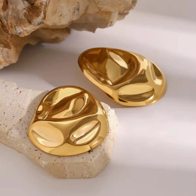 Gold earrings  for women on a textured surface with a neutral background