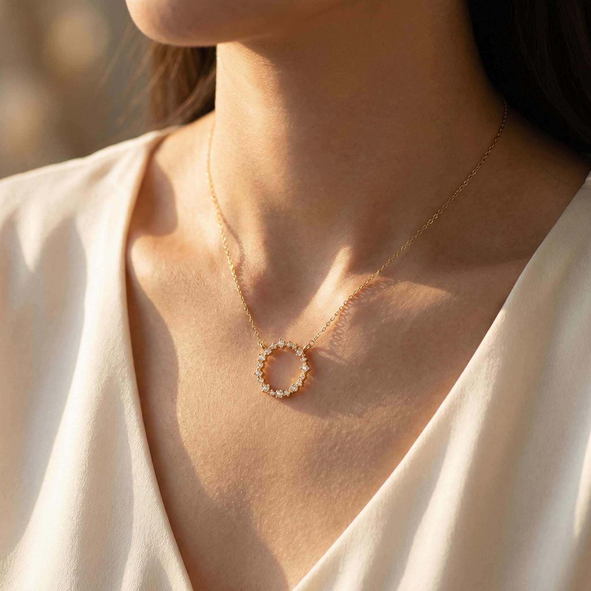 A close-up of a woman wearing a delicate gold necklace with a circular floral pendant, perfect for adding elegance to any look.