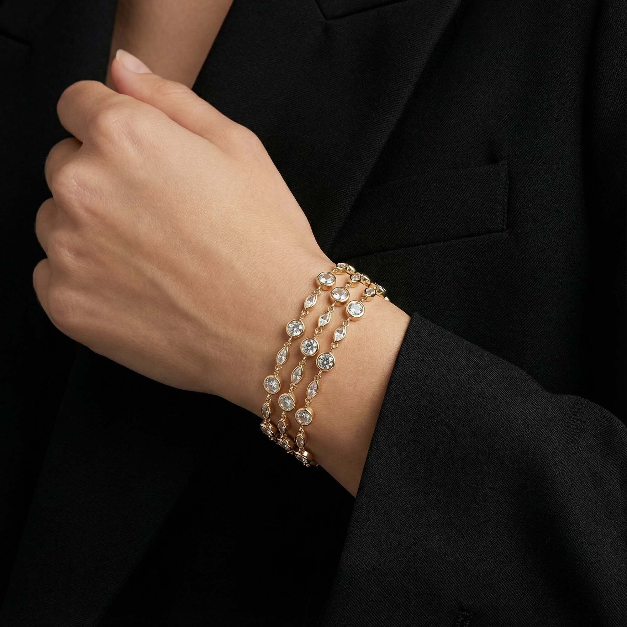 Close-up of a hand wearing multiple diamond bracelets on a black background