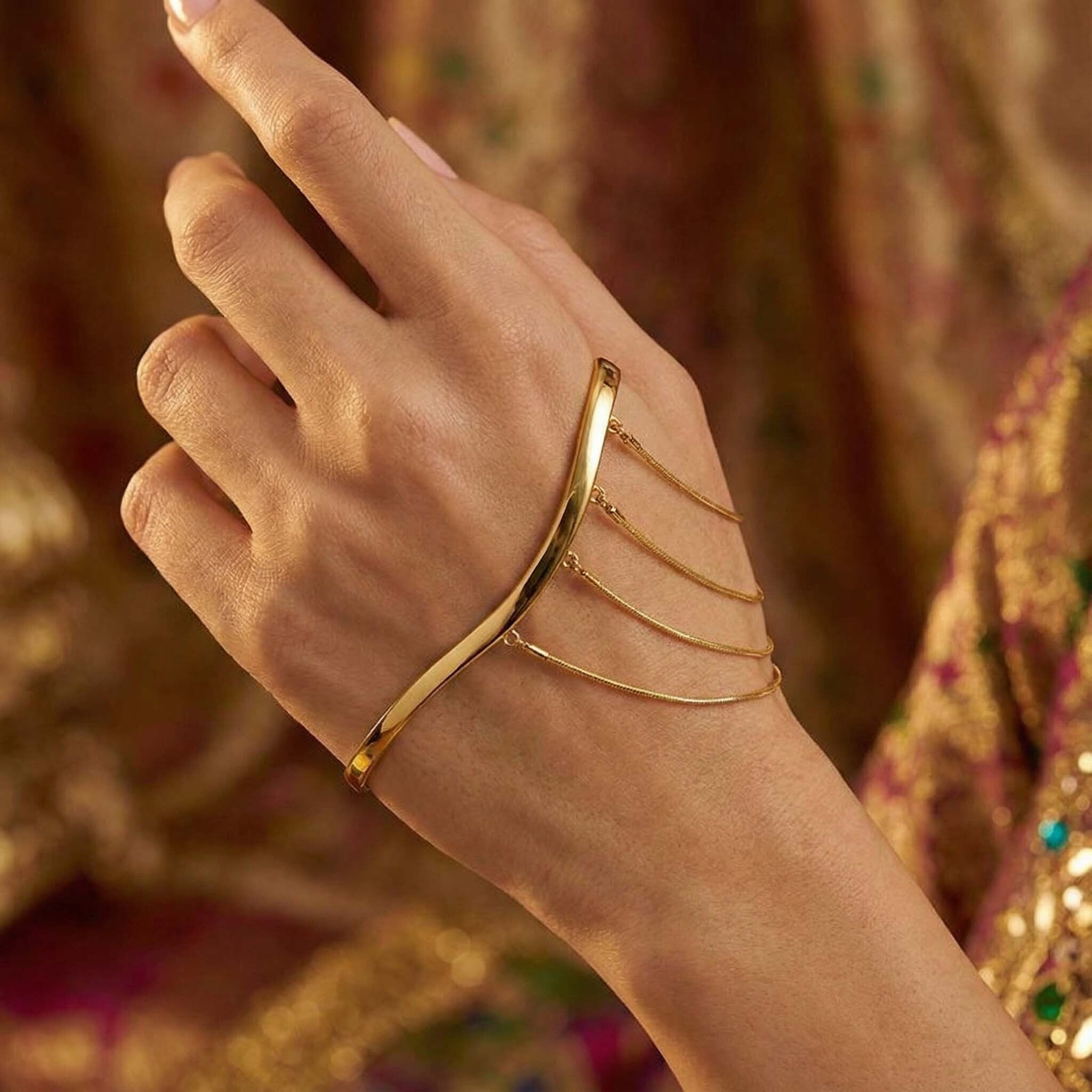 Gold bracelet on a hand with a blurred decorative background