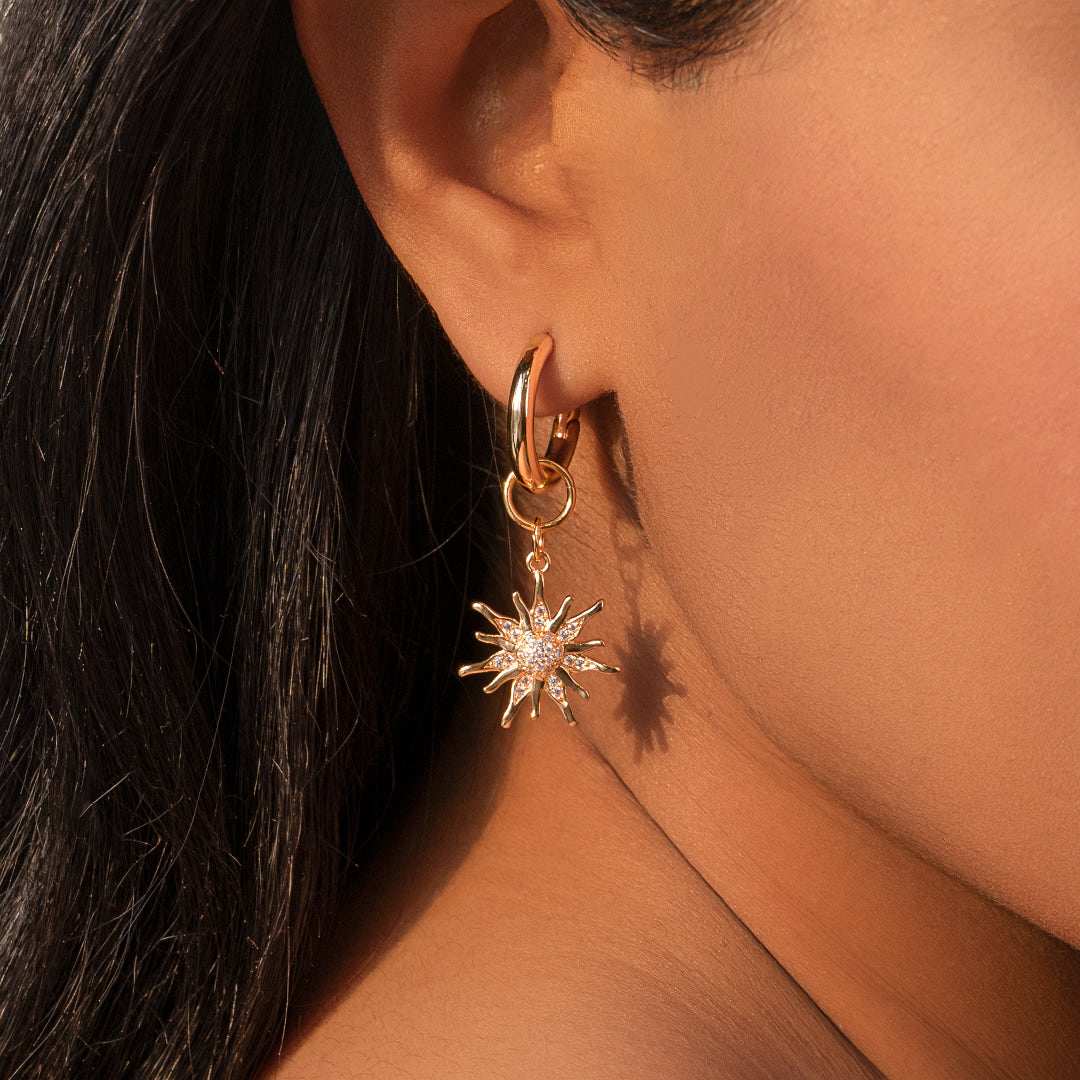 Close-up of a person wearing a gold hoop earring with a star-shaped pendant.