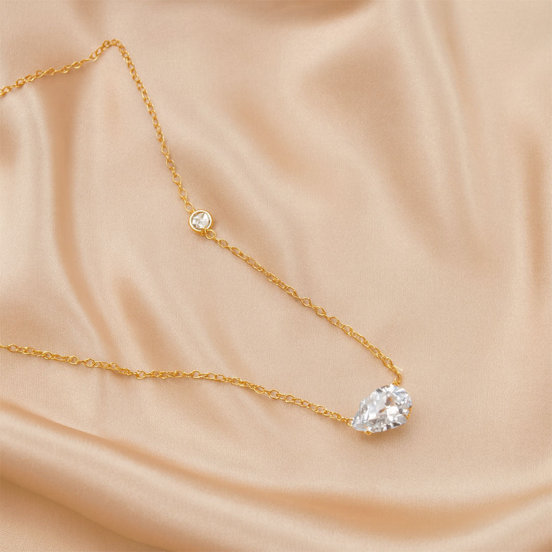 Gold necklace with diamond pendants on a beige fabric background