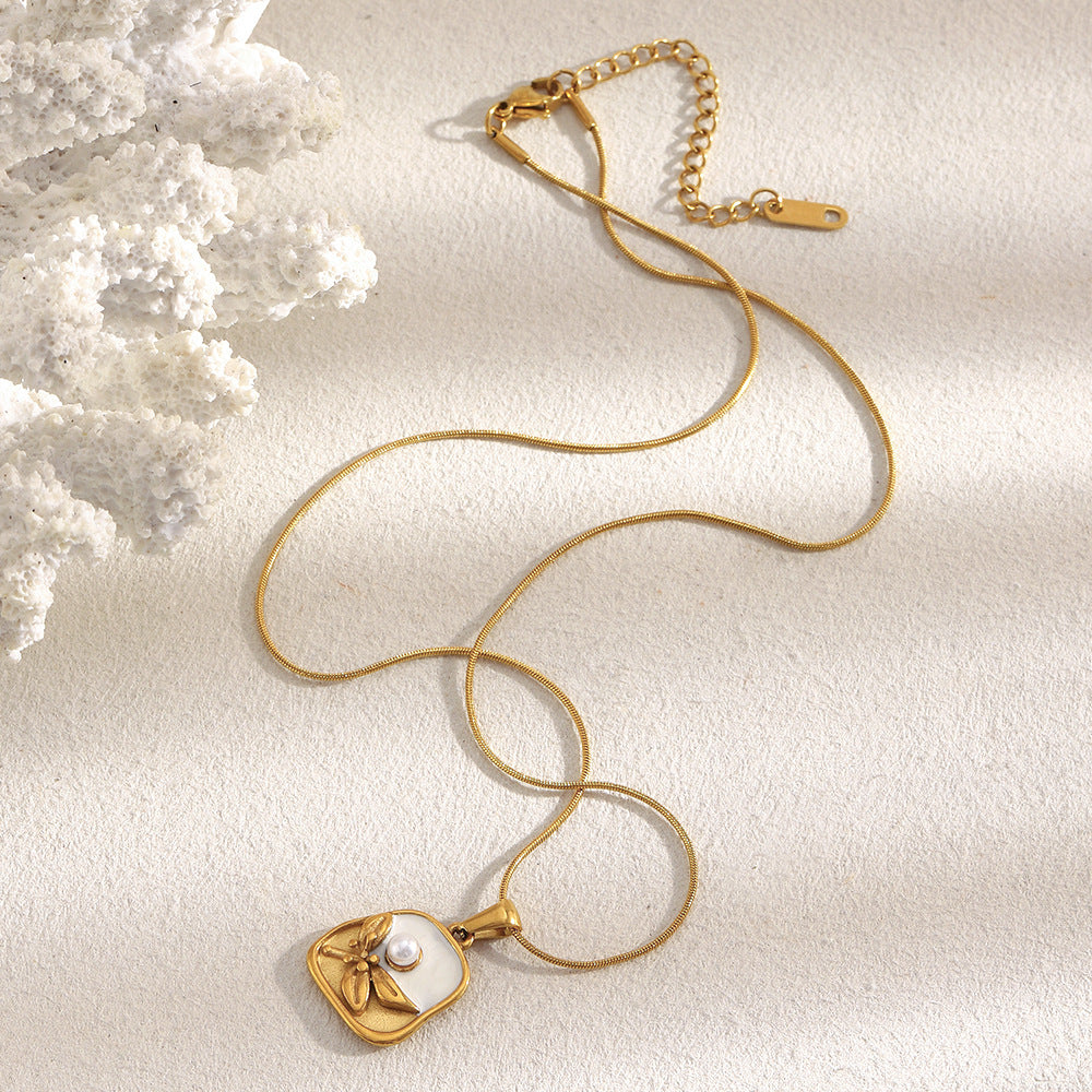 Gold necklace for women with a heart-shaped pendant on a textured beige surface