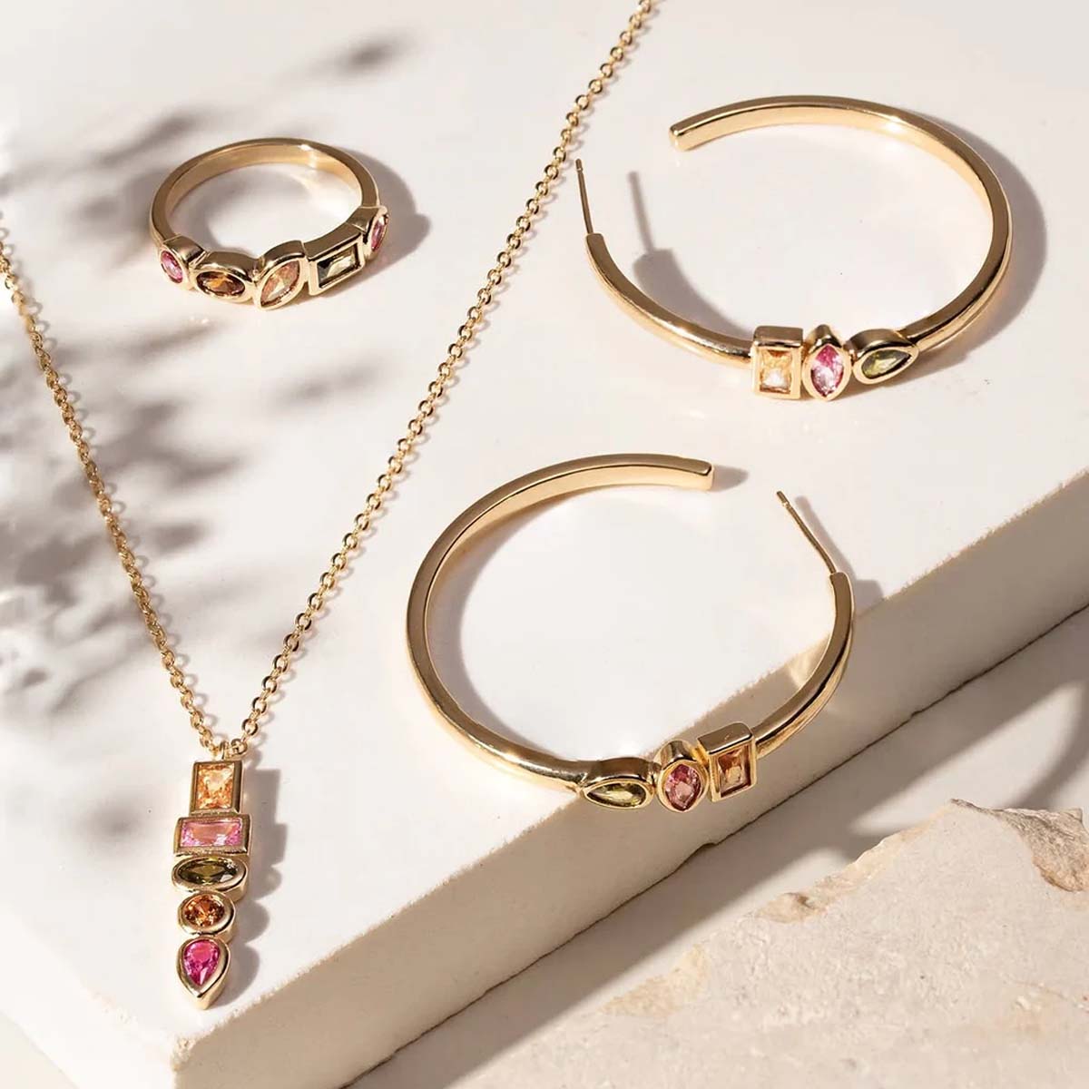 Gold jewelry set with rings and necklace on a textured surface